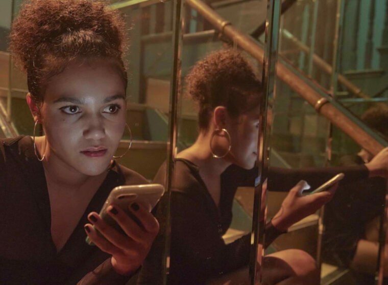 Emma McDonald siting on steps beside a mirror holding her phone in 7 Keys | Agents of Fandom