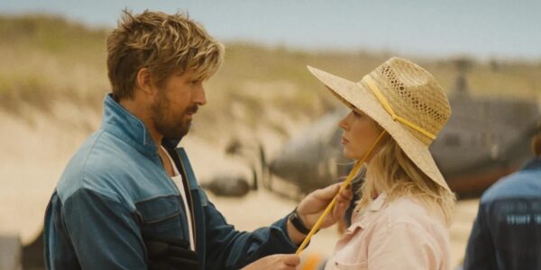 Colt Seavers (Ryan Gosling, left) attempts to woo Jody Moreno (Emily Blunt, right) with his cool-guy stunts as he tightens the rope on her sunhat in The Fall Guy I Agents of Fandom
