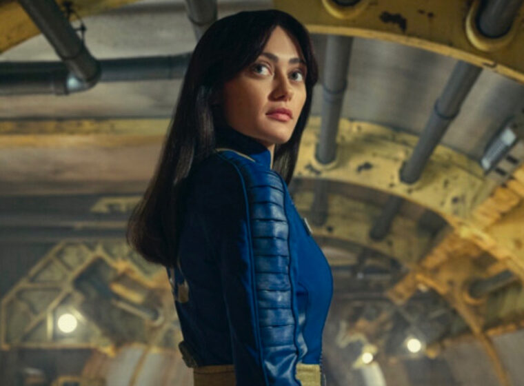 Ella Purnell as Lucy standing inside a vault looking over her shoulder in Fallout | Agents of Fandom