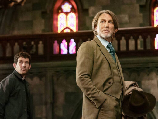 Jud Duplenticy (Josh O'Connor) and Benoit Blanc (Daniel Craig) staring at the front of a church in Wake Up Dead Man: A Knives Out Mystery | Agents of Fandom