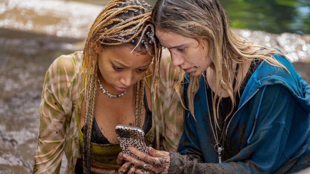 Amandla Stenberg (left) and Maria Bakalova (right) check their phone in desperate hopes of wifi or cell service.