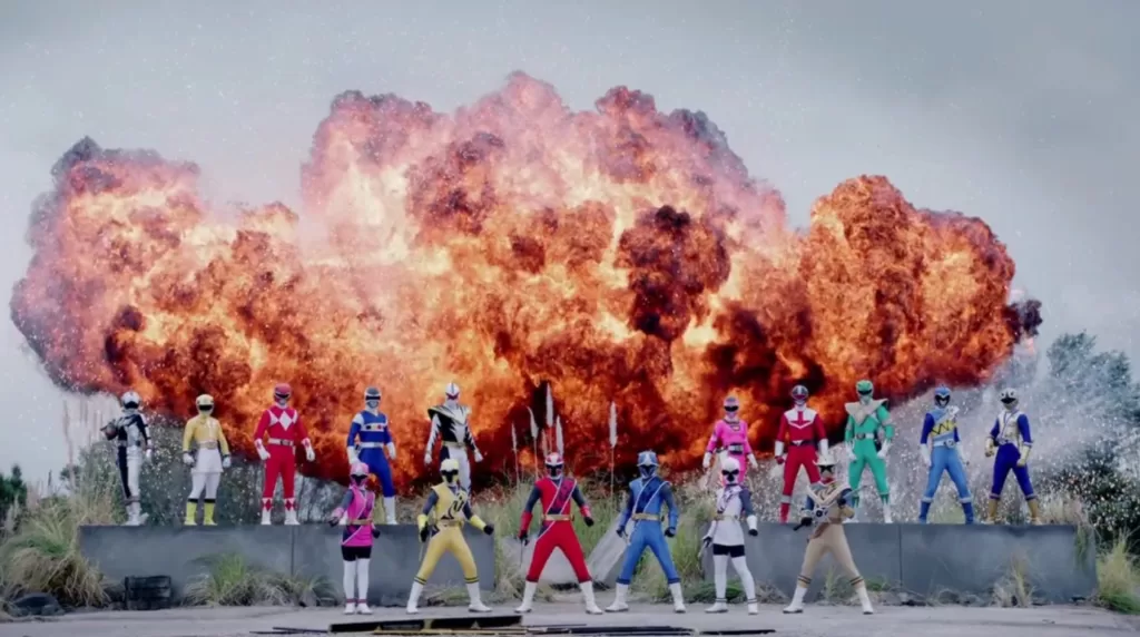 A collection of veteran Power Rangers, as well as the Super Ninja Steel Power Rangers team, standing in front of an explosion | Agents of Fandom