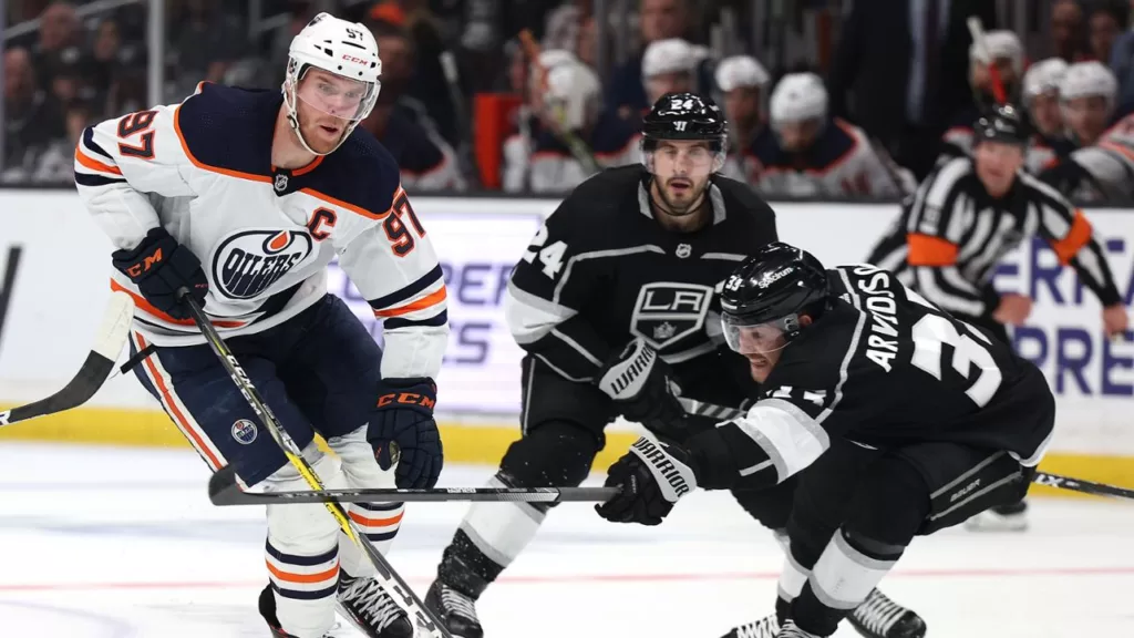 Los Angeles Kings winger Viktor Arvidsson (33) reaches to try and take the puck away from Edmonton Oilers Captain Connor McDavid (97) as Kings center Phillip Danault (24) looks on | Agents of Fandom