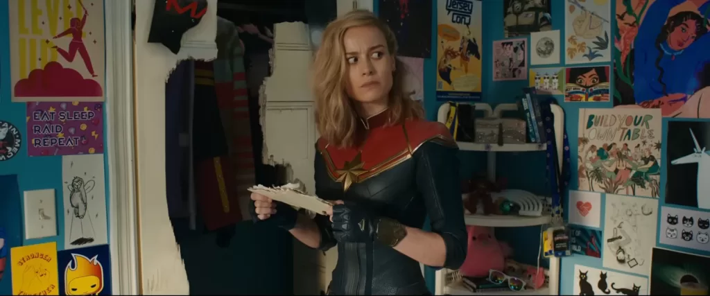 Brie Larson as Captain Marvel holding a piece of paper in Kamala Khan's bedroom in a scene in 'The Marvels' | Agents of Fandom