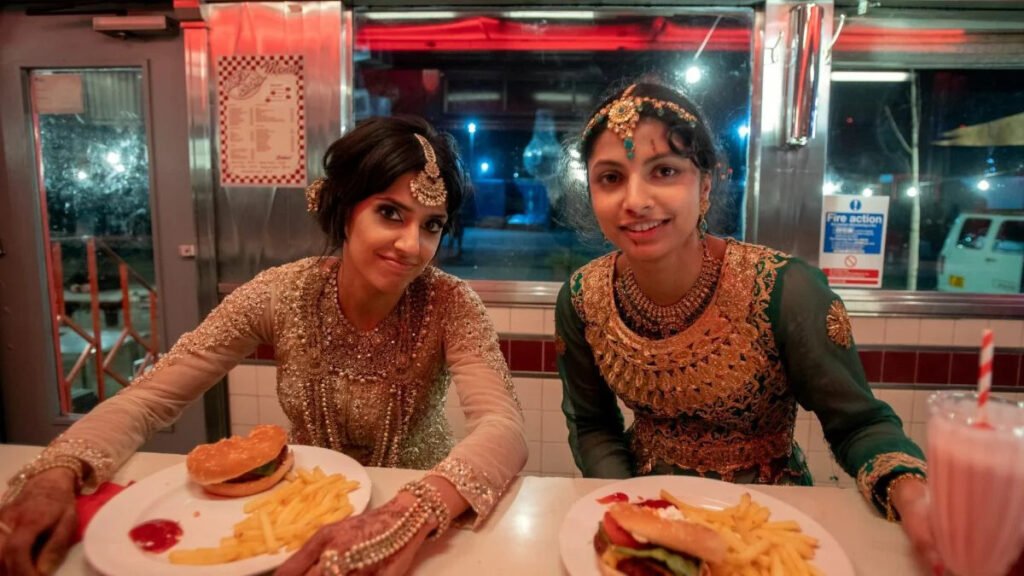 Ritu Arya and Priya Kansara taking a picture together to commemorate their time on Polite Society. According to Priya Kansara, this scene was filmed on the last day of the shoot. At this point, the sisterhood between her and Ritu Arya was at its peak. They both gained a sibling filming this movie and there's nothing more evident of this on screen than the finale of the movie. | Agents of Fandom