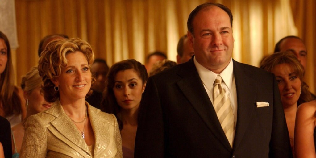 Edie Falco and James Gandolfini standing together at a celebration in front of a crowd in The Sopranos | Agents of Fandom