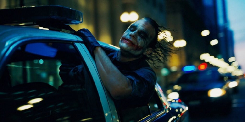 Heath Ledger as the Joker hanging his head out the window in The Dark Knight | Christopher Nolan movies | Agents of Fandom