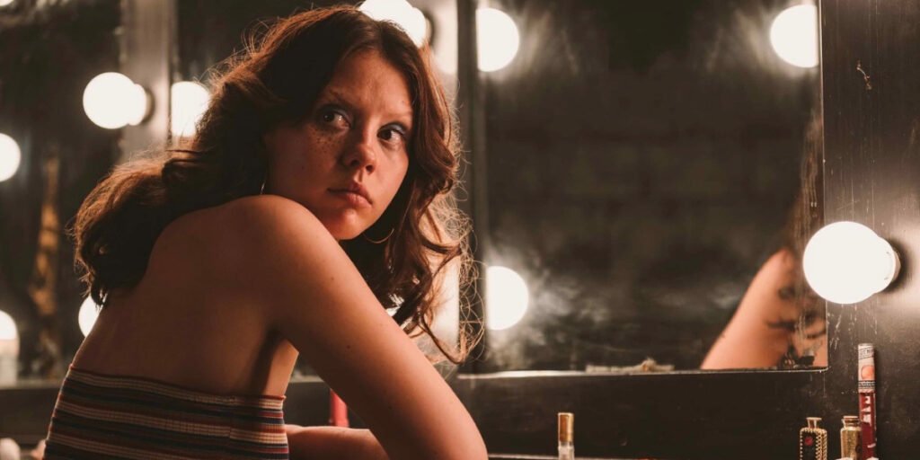 Mia Goth as Maxine/Pearl looking aaway from a mirror in X | Coming to Netflix February 2024 | Agents of Fandom