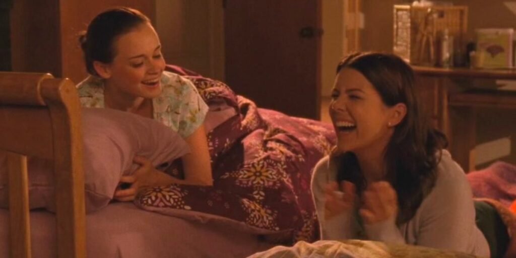 A unique iconic female TV duo, Rory and Lorelei laughing it up in Rory's college dorm during her first night at Yale in Gilmore Girls | Agents of Fandom