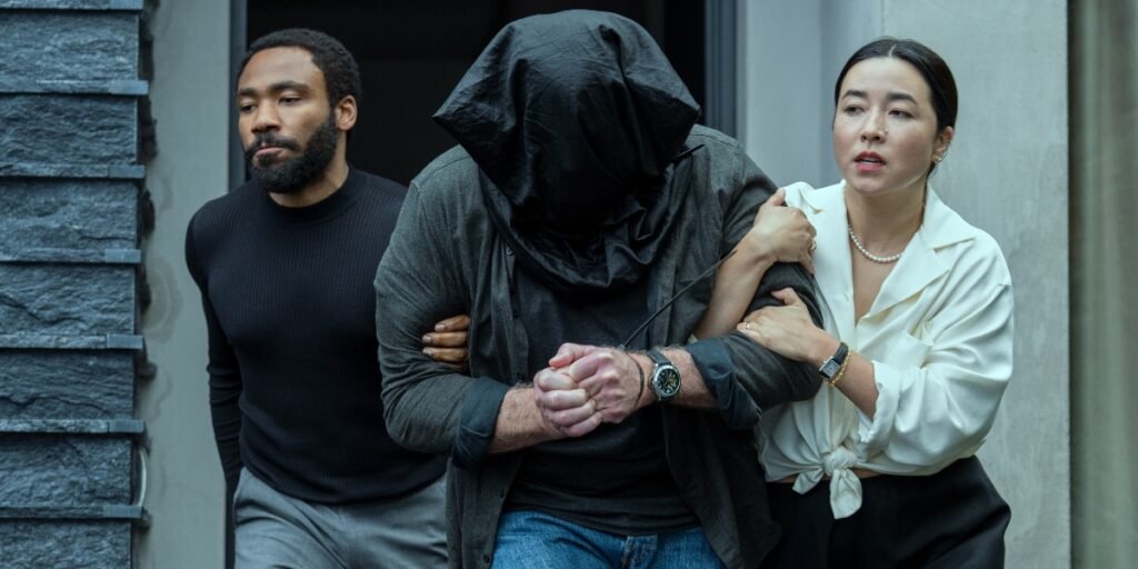 Donald Glover and Maya Erskine escorting a hostage with a bag on his head in Mr. and Mrs. Smith | Agents of Fandom