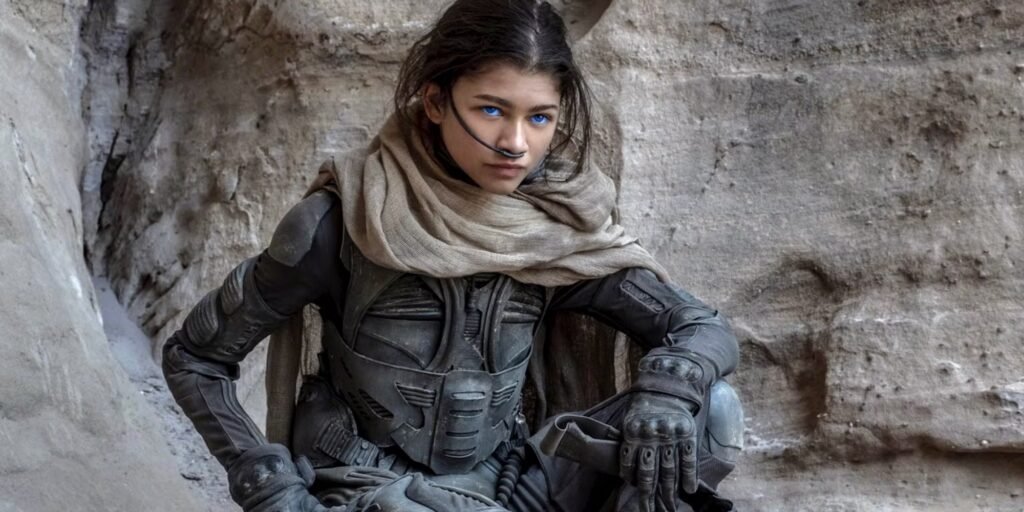 Zendaya as Chani in Dune sat in her uniform against a rock | Agents of Fandom