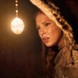 Millie Bobby Brown holding up a light in Damsel | Agents of Fandom