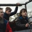 Paul (Nic Cage, left), Thomas (Maxwell Jenkins, center), and Joseph (Jaeden Martell, right) practice driving a small offroad vehicle through a valley in a post-apocalyptic world | Agents of Fandom