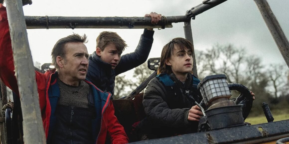 Paul (Nic Cage, left), Thomas (Maxwell Jenkins, center), and Joseph (Jaeden Martell, right) practice driving a small offroad vehicle through a valley in a post-apocalyptic world | Agents of Fandom