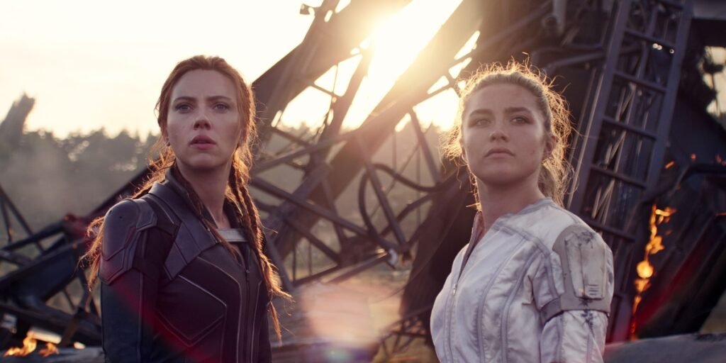 A redheaded woman in a black jumpsuit (Scarlett Johansson) and a blonde woman in a white jumpsuit (Florence Pugh) stand in front of rubble | Agents of Fandom