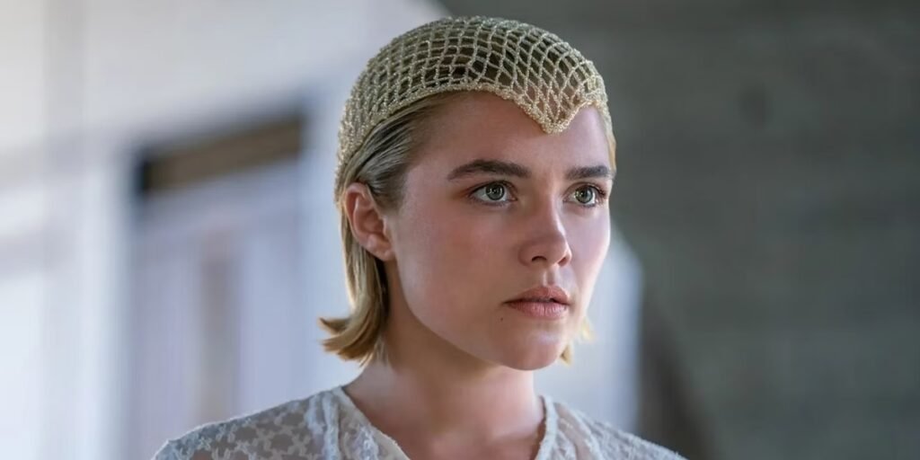 A young woman with short blonde hair (Florence Pugh) has a netlike accessory on her head. She wears a concerned expression on her face | Agents of Fandom 