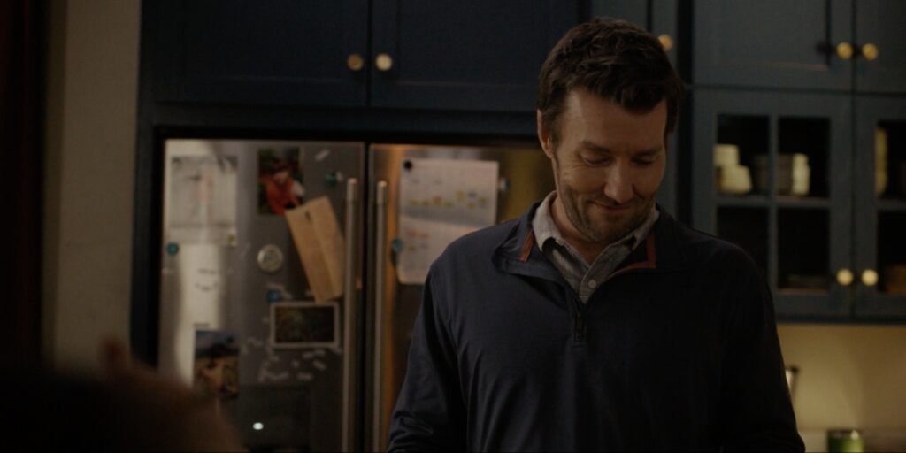 Joel Edgerton standing in a kitchen smiling looking down at the counter in Dark Matter Episode 1 | Agents of Fandom