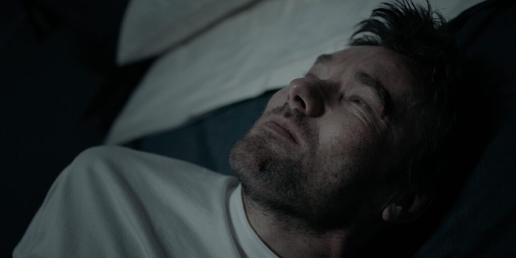 Joel Edgerton as Jason Dessen laying on a bed with a painful look on his face in Dark Matter Episode 3 | Agents of Fandom
