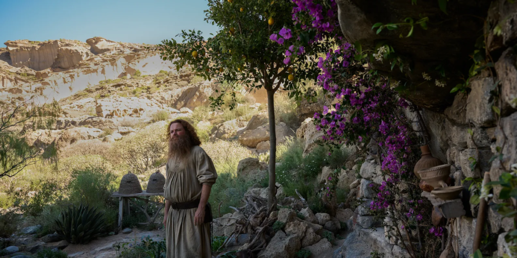 Tom Bombadil standing in front of his home the Underhill on the edge of the old forest in The Rings of Power Season 2 | Agents of Fandom
