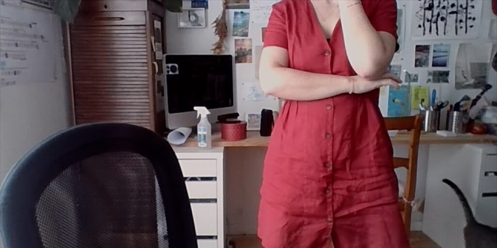 Patricia Franquesa stands in a red jumpsuit near her desk in her bedroom, pondering her next move to avoid having personal photos released of her. I Agents of Fandom