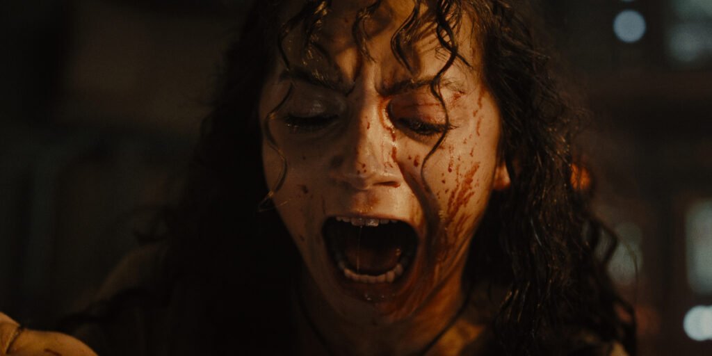 A bloody-faced Isabela Merced screaming at a terrifying sight in Alien: Romulus | Agents of Fandom