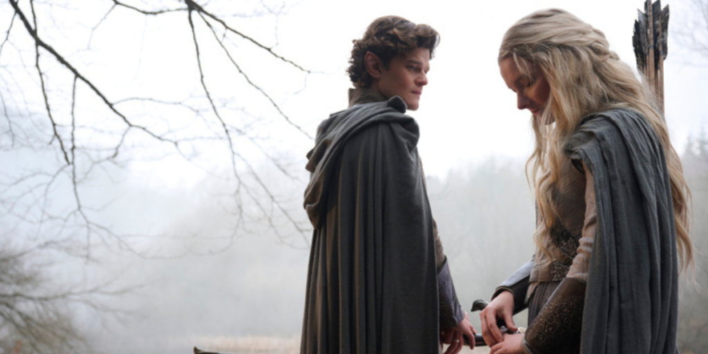 Robert Aramayo as Elrond and Morfydd Clark as Galadriel talking to each other in the woods while Galadriel stares at her rings | Agents of Fandom.