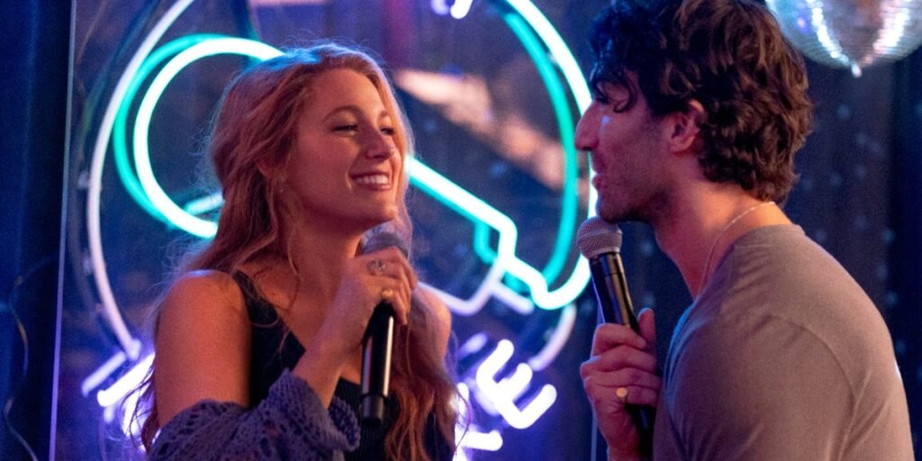 Blake Lively and Justin Baldoni in a karaoke bar scene from It Ends with Us, each holding microphone. Lively is smiling brightly | Agents of Fandom