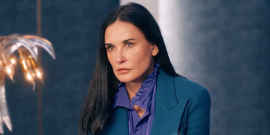 Demi Moore clenching her jaw in a blue suit in The Substance | Agents of Fandom