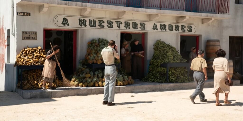 Allerton (Drew Starkey) takes a picture of an old building in Mexico City as the piles of fruit overflow outside of it. I Agents of Fandom