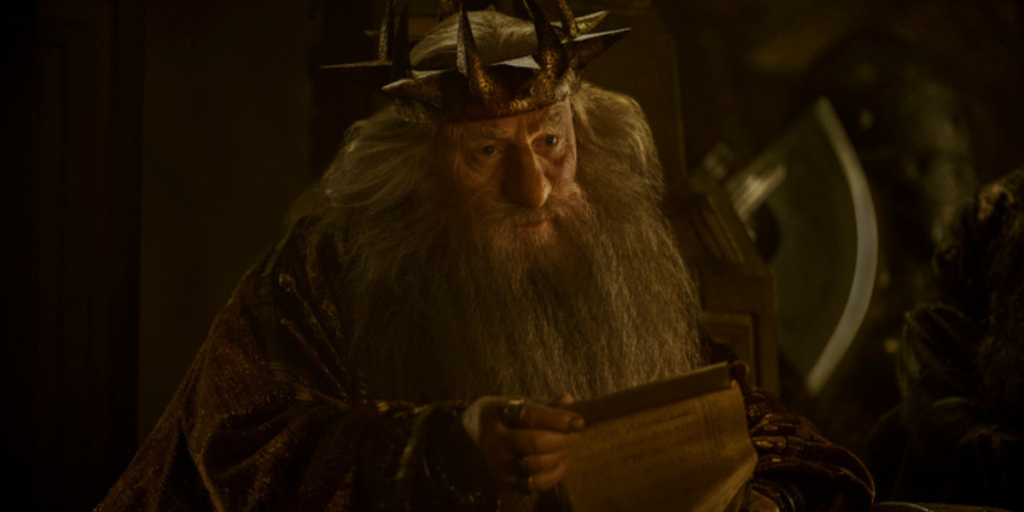 Peter Murray as King Durin III reading over a proposal from a scroll as he sits on his throne | Agents of Fandom