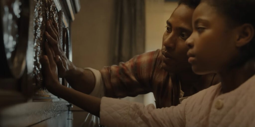 Boy Willie (John David Washington) and Maretha (Skylar Aleece Smith) looking at the carvings on the piano in The Piano Lesson | Agents of Fandom