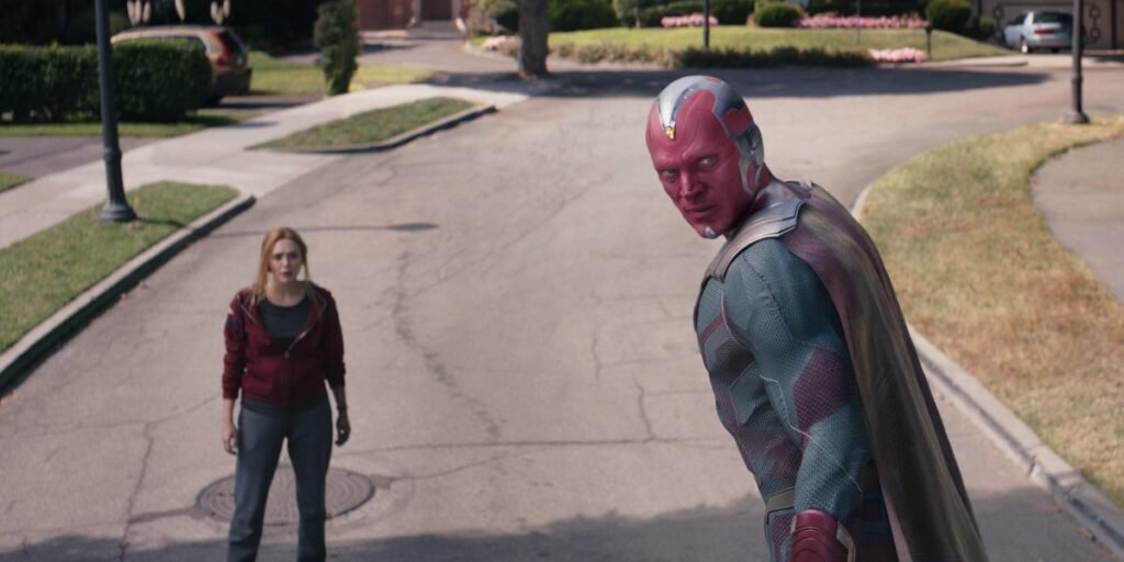 Paul Bettany as Vision flying in the air whilst Elizabeth Olsen is stood on the ground ahead of their battle with Agatha in WandaVision | Agents of Fandom