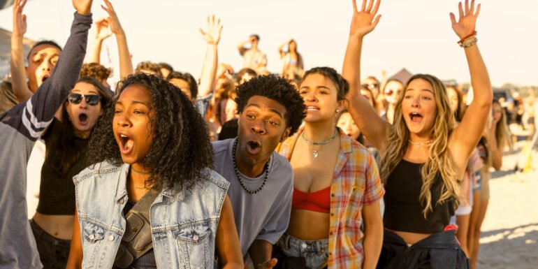 Pogues raising their hands and celebrating on the beach in Outer Banks Season 4 | Agents of Fandom