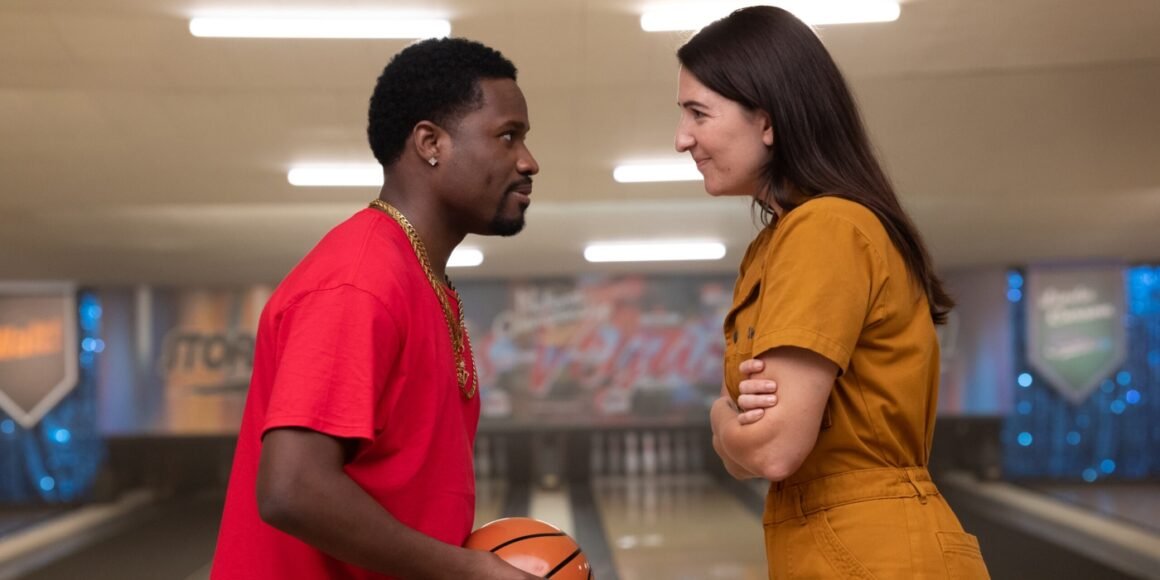 Walt (Shameik Moore) holding a bowling ball designed as a basketball while smiling at Skunk (D'Arcy Carden) in The Gutter | Agents of Fandom