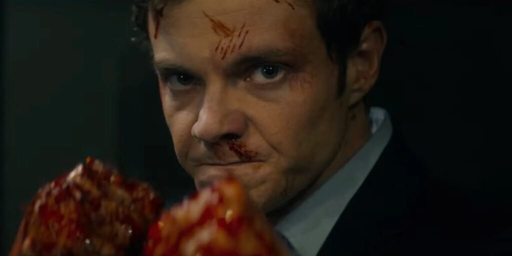 Jack Quaid raises his bloodied fists during a fight as he is ready to continue battling  in Novocaine  I Agents of Fandom