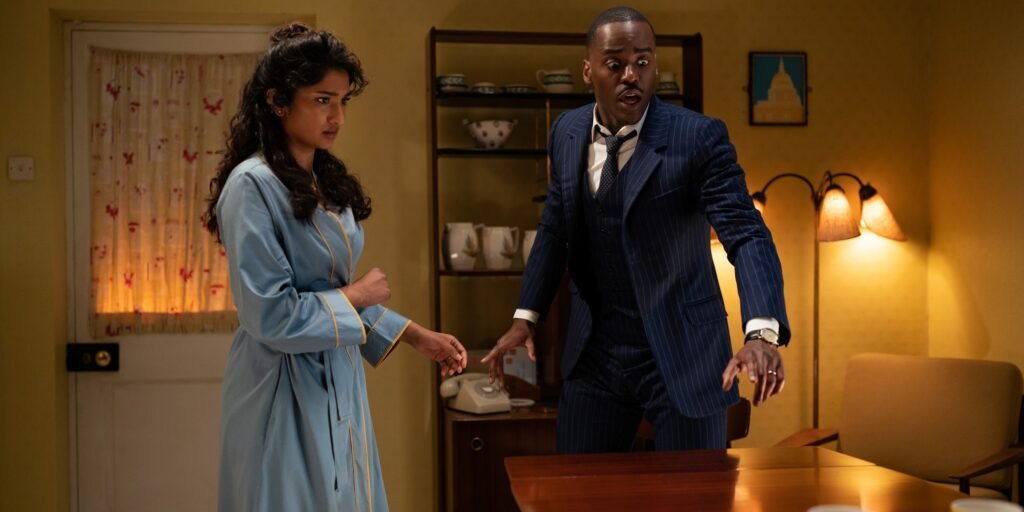 Belinda (Varada Sethu) and the Doctor (Ncuti Gatwa) staring at a table in Doctor Who Season 2 Episode 7, "Wish World" | Agents of Fandom