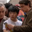Mr. Han (Jackie Chan) and Daniel LaRusso (Ralph Macchio) looking at a pamphlet while Li Fong (Ben Wang) watches a fight in Karate Kid: Legends | Agents of Fandom