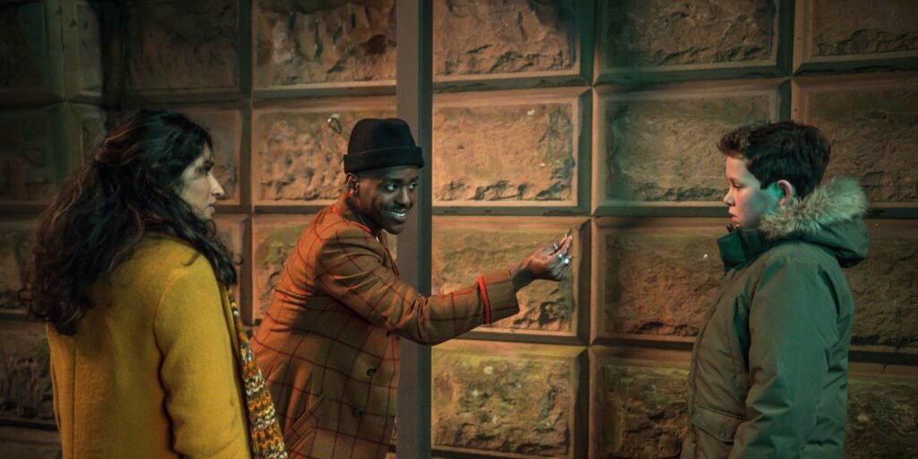 The Doctor with Belinda passing a coin to Conrad in Doctor Who Season 2, Episode 4, "Lucky Day." | Agents of Fandom