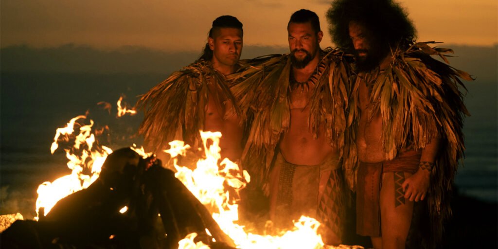 Jason Momoa standing in front of a fire with Te Kohe Tuhaka and Siua Ikale'o in Chief of War | Agents of Fandom