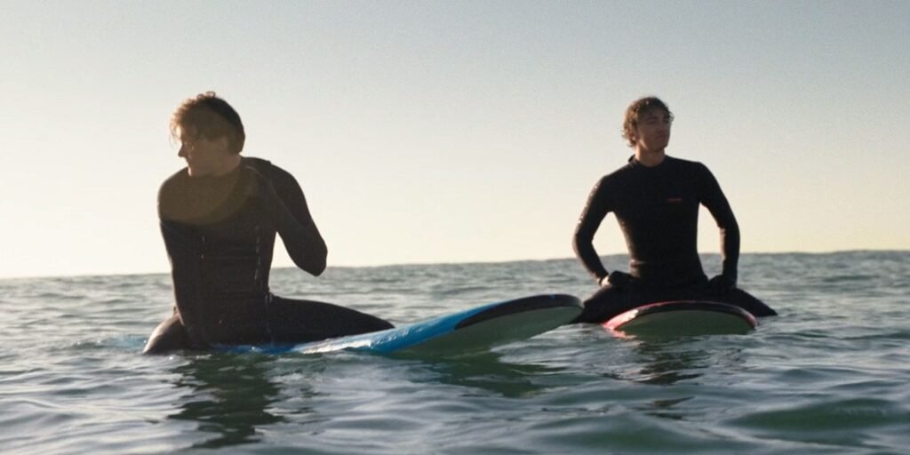 Conrad and Jeremiah (Gavin  sit on surfboards out in the ocean in The Summer I Turned Pretty Season 3 | Agents of Fandom