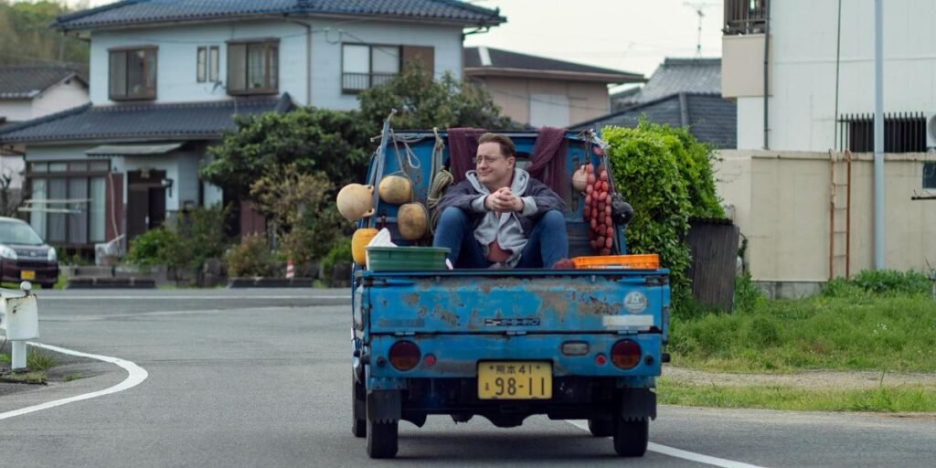 Brendan Fraser's Phillip rides in the back of a truck in Rental Family | Agents of Fandom