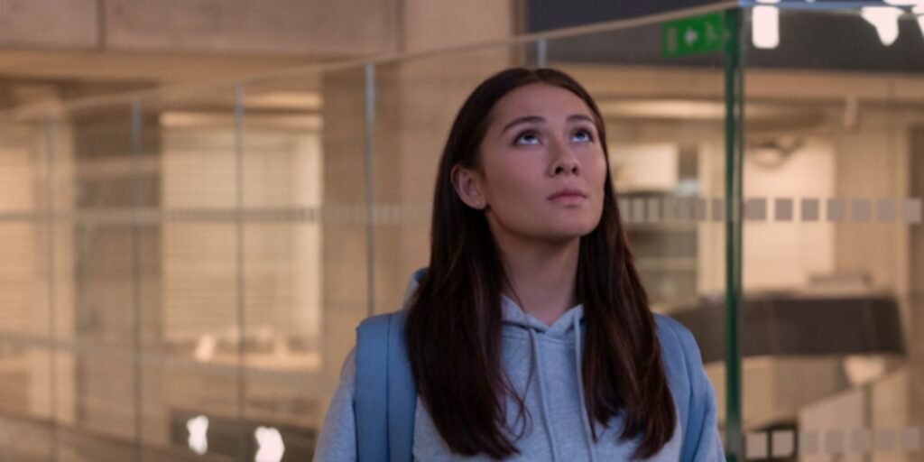Belly (Lola Tung) looks up at an airport screen. | Agents of Fandom.