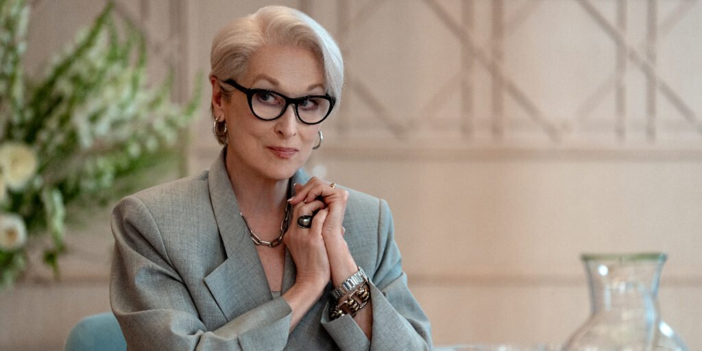 A woman sitting by a desk with his hands together.