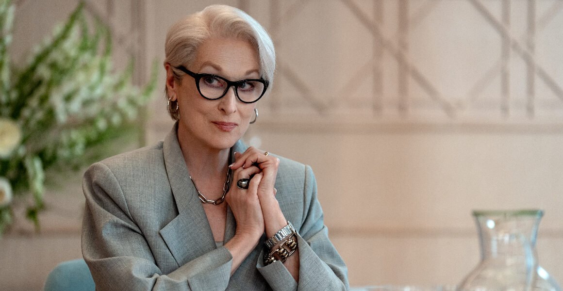 A woman sitting by a desk with his hands together.