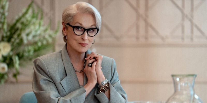 A woman sitting by a desk with his hands together.