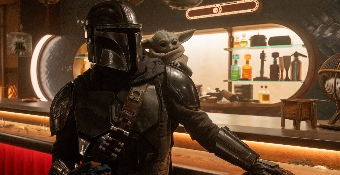 Din Djarin and Grogu in a Star Wars cantina in The Mandalorian and Grogu | Agents of Fandom
